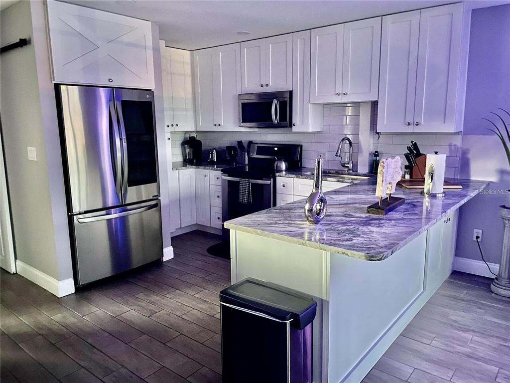A kitchen features white cabinets, stainless steel appliances, and a marble-patterned island countertop — 2595 CYPRUS DRIVE UNIT 4-217, PALM HARBOR, FL