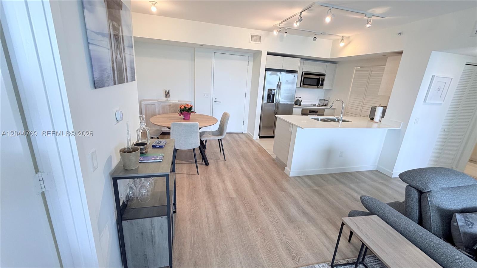 An open-concept kitchen and dining area features light wood flooring and modern white cabinetry — 4250 Biscayne Blvd # 1617, Miami FL 33137, MIAMI, FL