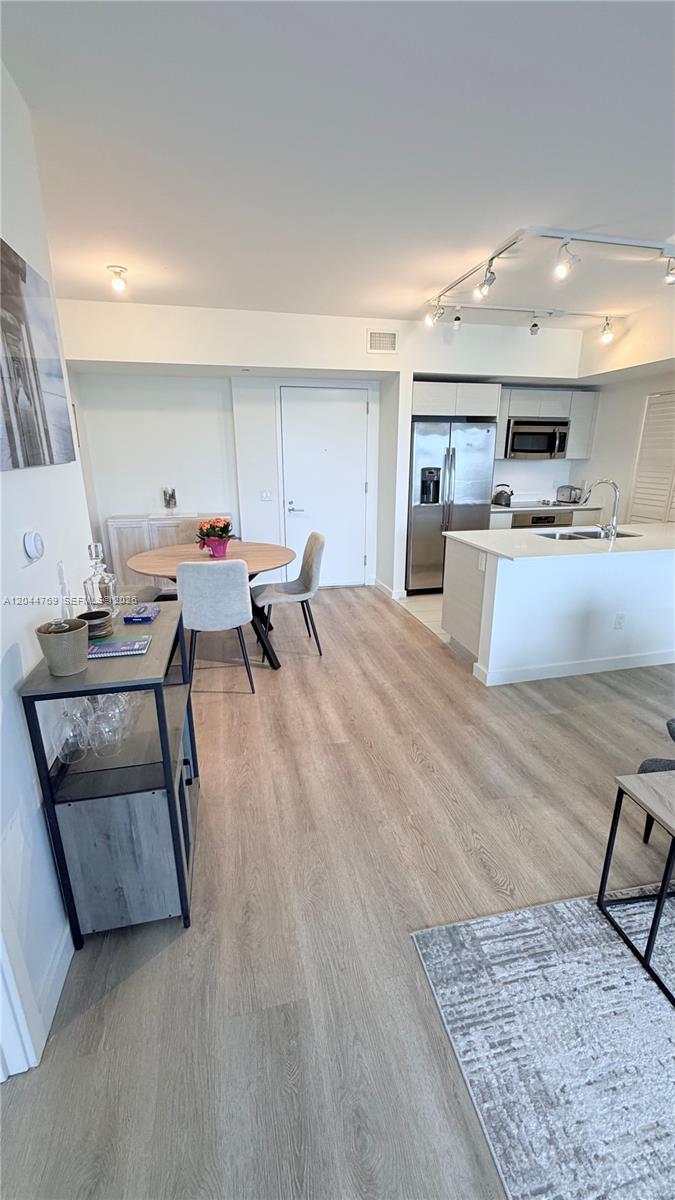 An open-concept kitchen and dining area features light wood flooring and modern stainless steel appliances — 4250 Biscayne Blvd # 1617, Miami FL 33137, MIAMI, FL