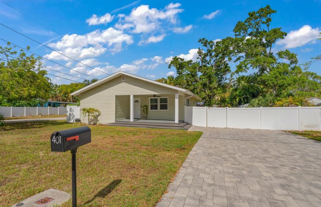 A single-story house with light green siding, a front porch, and a paved driveway — 401 DEMPSEY ROAD, PALM HARBOR, FL