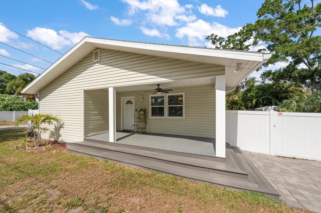 A light green house features a covered front porch with gray decking and white columns — 401 DEMPSEY ROAD, PALM HARBOR, FL