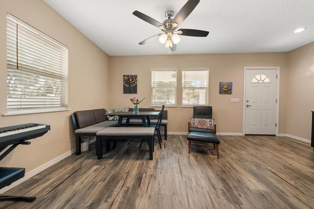 A dining area features a corner banquette, a table, wood-look flooring, and a ceiling fan — 401 DEMPSEY ROAD, PALM HARBOR, FL