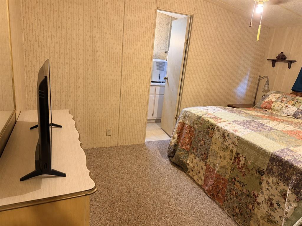 A bedroom features beige wallpaper, a floral quilt on the bed, and an attached bathroom — 355 NE 436 AVENUE, OLD TOWN, FL