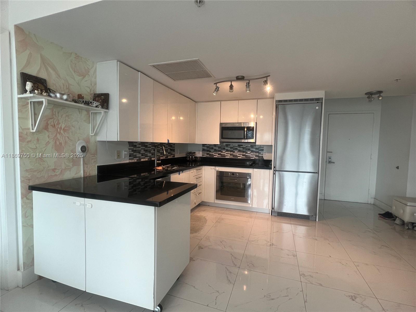 A kitchen features white cabinets, black countertops, stainless steel appliances, and light marble flooring — 92 SW 3rd St # 3803, Miami FL 33130, MIAMI, FL
