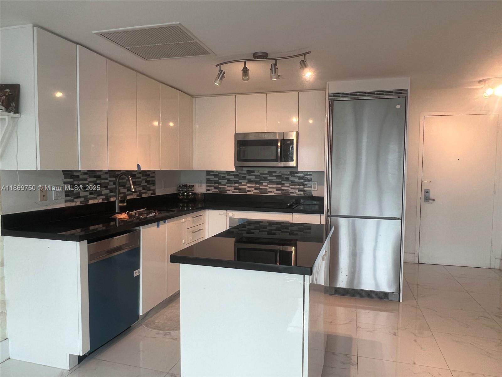 A modern kitchen features white cabinets, black countertops, stainless steel appliances, and a central island — 92 SW 3rd St # 3803, Miami FL 33130, MIAMI, FL