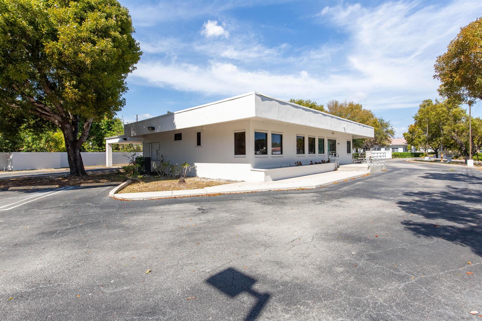 A white, single-story commercial building with a flat roof sits in a paved parking lot — 2419 S Seacrest Boulevard, Boynton Beach FL 33435, BOYNTON BEACH, FL