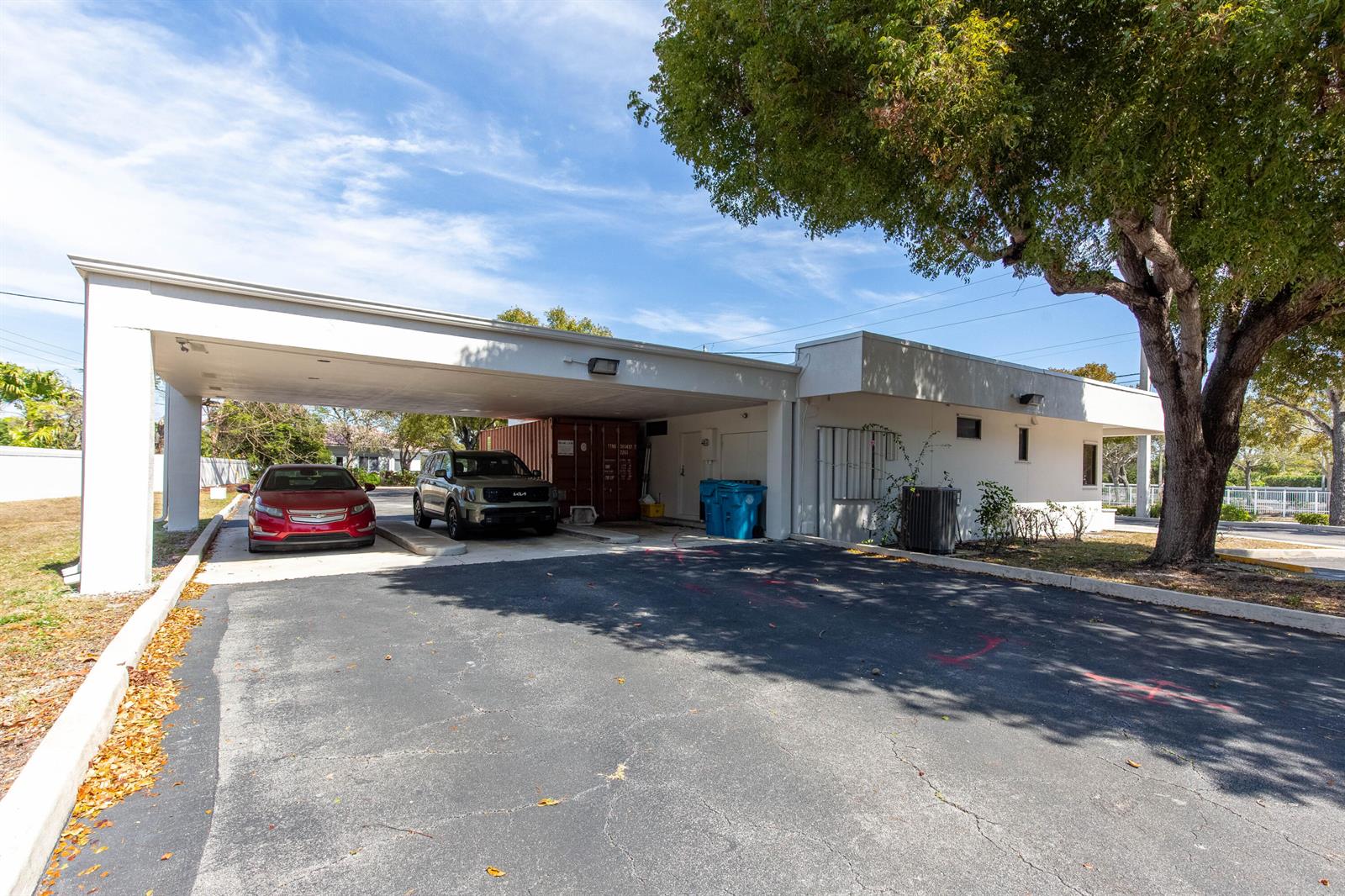 A white building features a large covered carport with two parked cars and a storage container — 2419 S Seacrest Boulevard, Boynton Beach FL 33435, BOYNTON BEACH, FL
