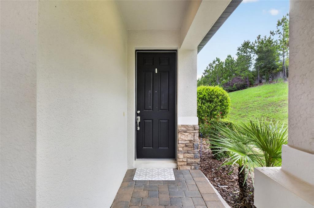 A black front door with a stone base sits at the end of a porch — 2612 FRAZEEK COURT, CLERMONT, FL
