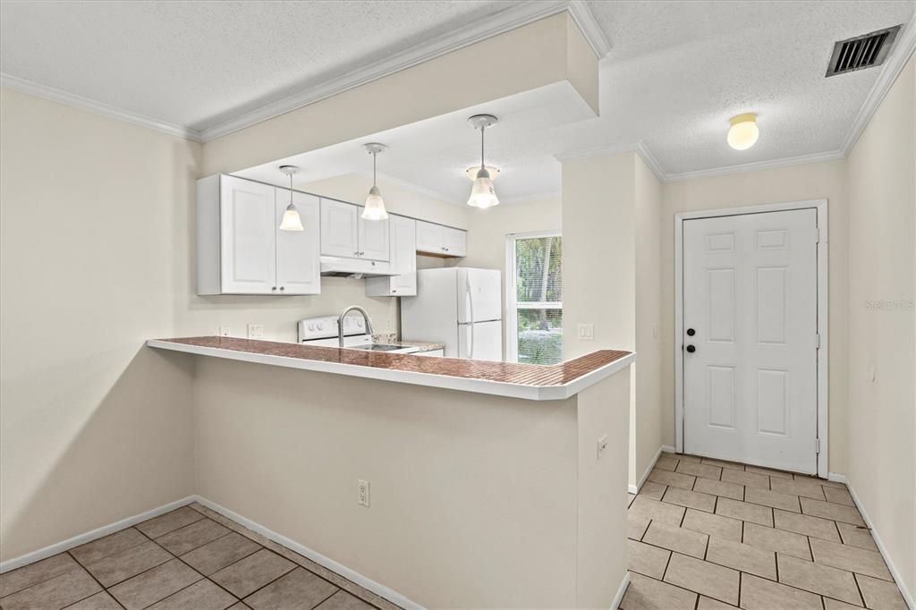 A kitchen with white cabinets, a breakfast bar, and tile flooring near an entry door — 4631 SUMMERWIND DRIVE UNIT 16, SARASOTA, FL