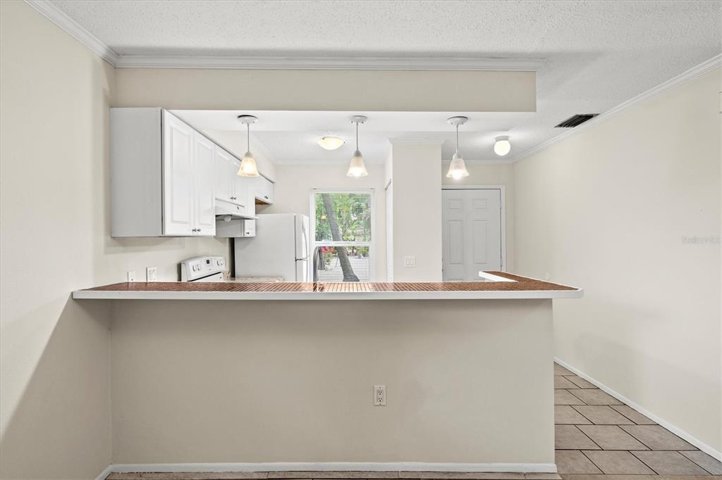 A kitchen with white cabinets and a breakfast bar overlooks a dining area with tile — 4631 SUMMERWIND DRIVE UNIT 16, SARASOTA, FL