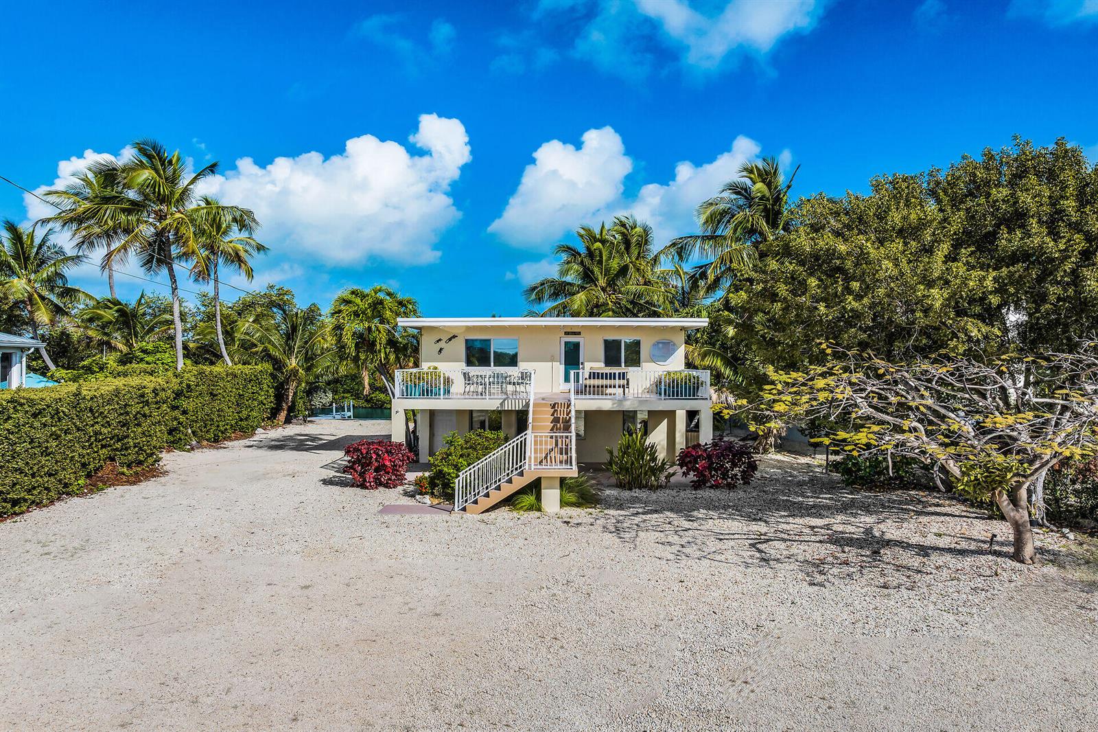 A two-story house with a raised deck and white railings sits on a gravel lot — 77340 Overseas Highway, Islamorada FL 33036, ISLAMORADA, FL