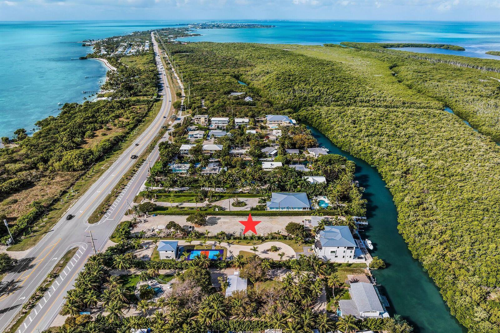 An aerial view shows a vacant lot marked with a red star near a canal — 77340 Overseas Highway, Islamorada FL 33036, ISLAMORADA, FL