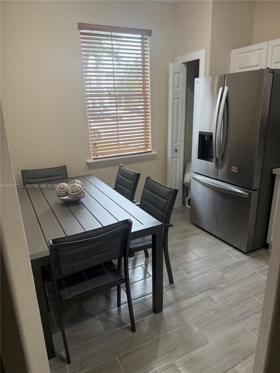A dining area features a dark table with four chairs, tile flooring, and a stainless refrigerator — 5400 NW 107th Ave # 416, Doral FL 33178, DORAL, FL