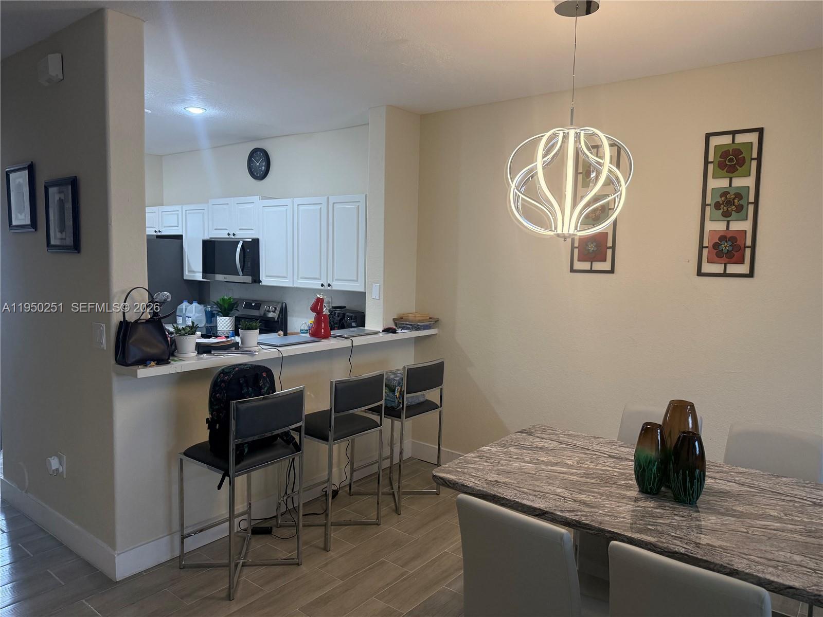 A dining area with a stone-topped table and breakfast bar adjacent to a white kitchen — 5400 NW 107th Ave # 416, Doral FL 33178, DORAL, FL