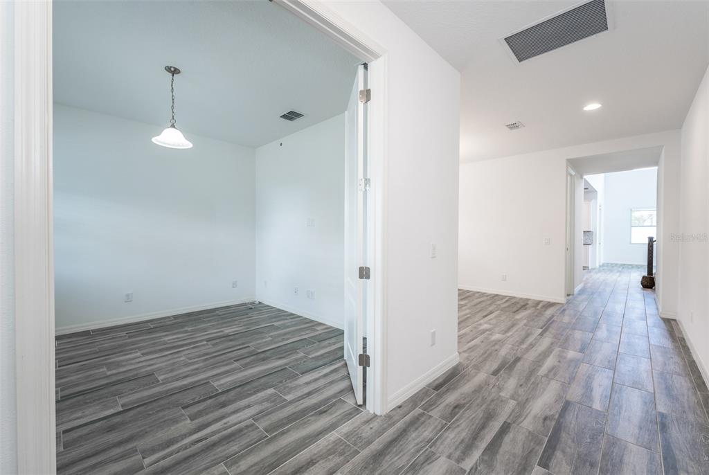 A room with a pendant light and gray wood-look tile flooring viewed from a hallway — 15372 SUGAR CITRUS DRIVE, WINTER GARDEN, FL