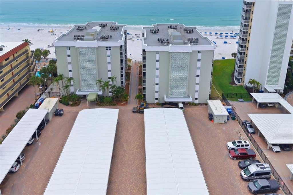 An aerial view shows two light-green apartment buildings situated near a sandy beach — 6312 MIDNIGHT PASS ROAD UNIT 305S, SARASOTA, FL
