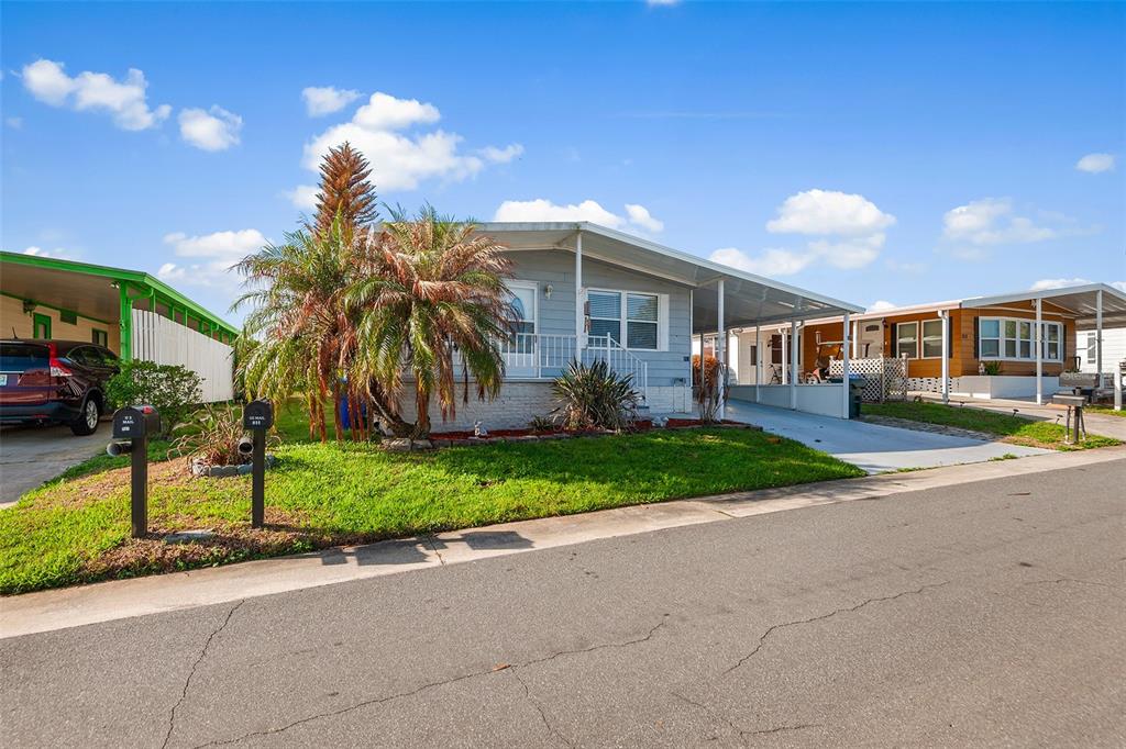 A light blue manufactured home features a palm tree, a carport, and a grassy lawn — 914 PINE RIDGE DRIVE, LAKELAND, FL
