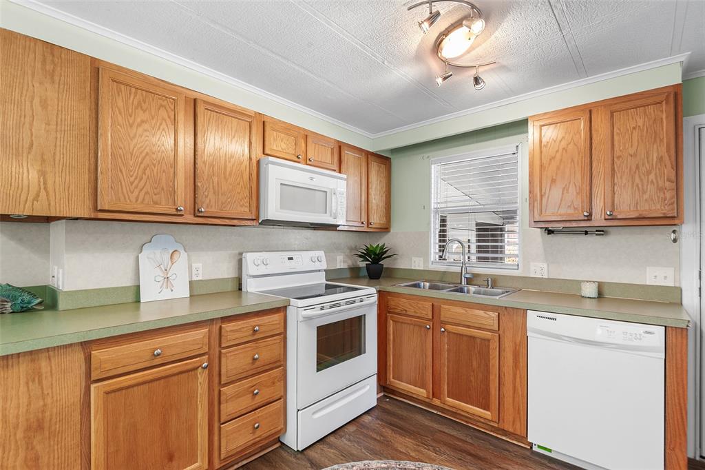 A kitchen with wood cabinets, white appliances, green countertops, and a double sink — 914 PINE RIDGE DRIVE, LAKELAND, FL