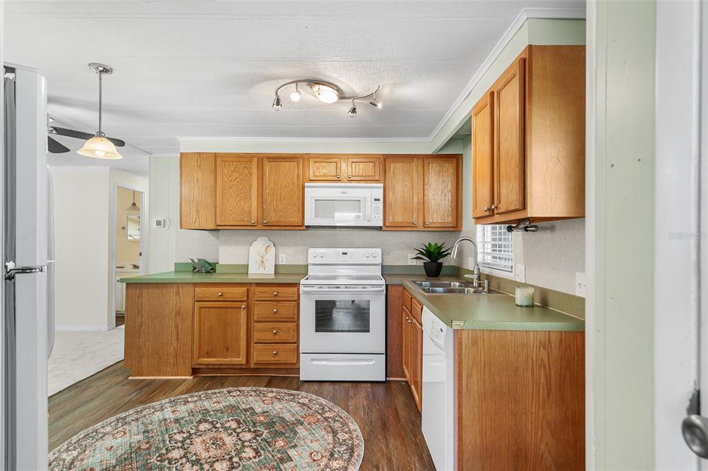 A kitchen features wood cabinets, green laminate countertops, white appliances, and a round patterned rug — 914 PINE RIDGE DRIVE, LAKELAND, FL