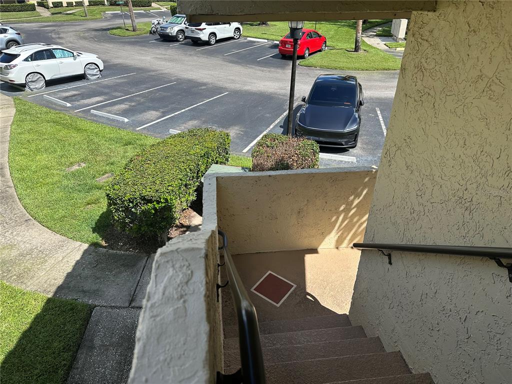 An outdoor staircase leads down to a parking lot with several parked cars — 3279 WESTRIDGE BOULEVARD UNIT 204, ORLANDO, FL
