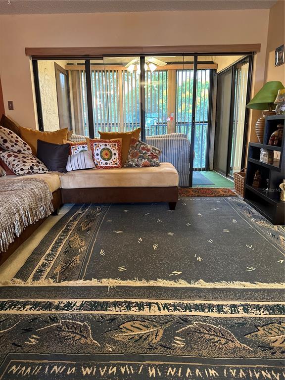 A living room features a large sectional sofa, a patterned area rug, and sliding glass doors — 3279 WESTRIDGE BOULEVARD UNIT 204, ORLANDO, FL