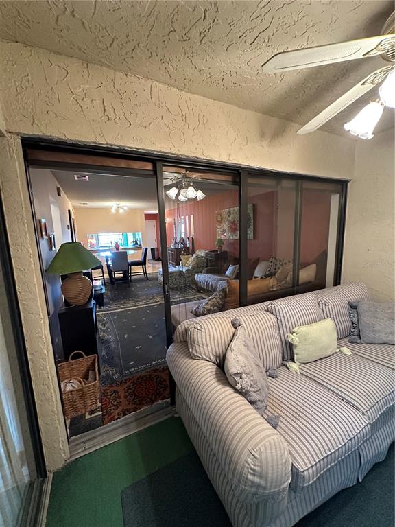 A sunroom with a striped sofa looks through sliding glass doors into a living area — 3279 WESTRIDGE BOULEVARD UNIT 204, ORLANDO, FL