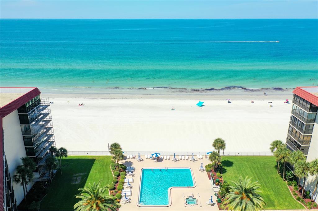An aerial view of a beachfront swimming pool with lounge chairs and the ocean beyond — 18304 GULF BOULEVARD UNIT 116, REDINGTON SHORES, FL