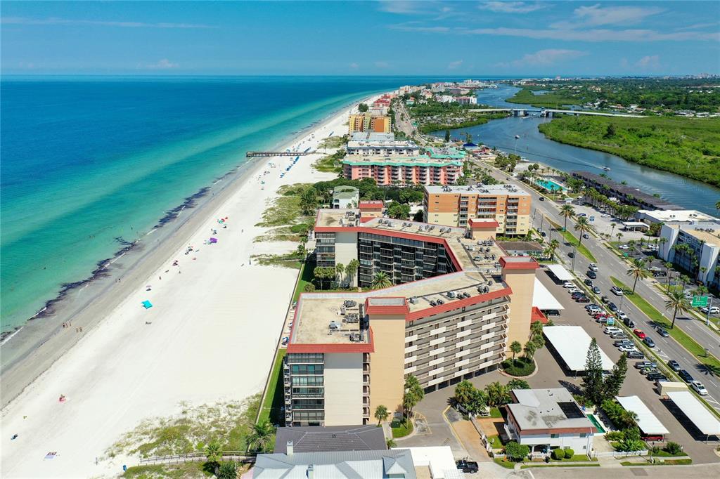 An aerial view of a beachfront condominium complex along a sandy coastline and a river — 18304 GULF BOULEVARD UNIT 116, REDINGTON SHORES, FL