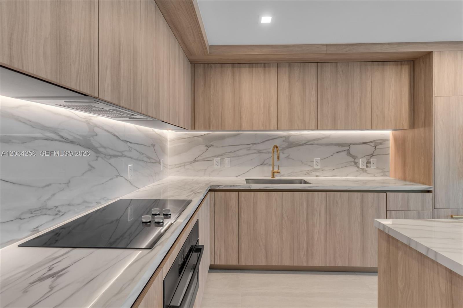 A modern kitchen features light wood cabinets, marble countertops, and a gold faucet — 77 SE 5 th st, Miami FL 33131, MIAMI, FL