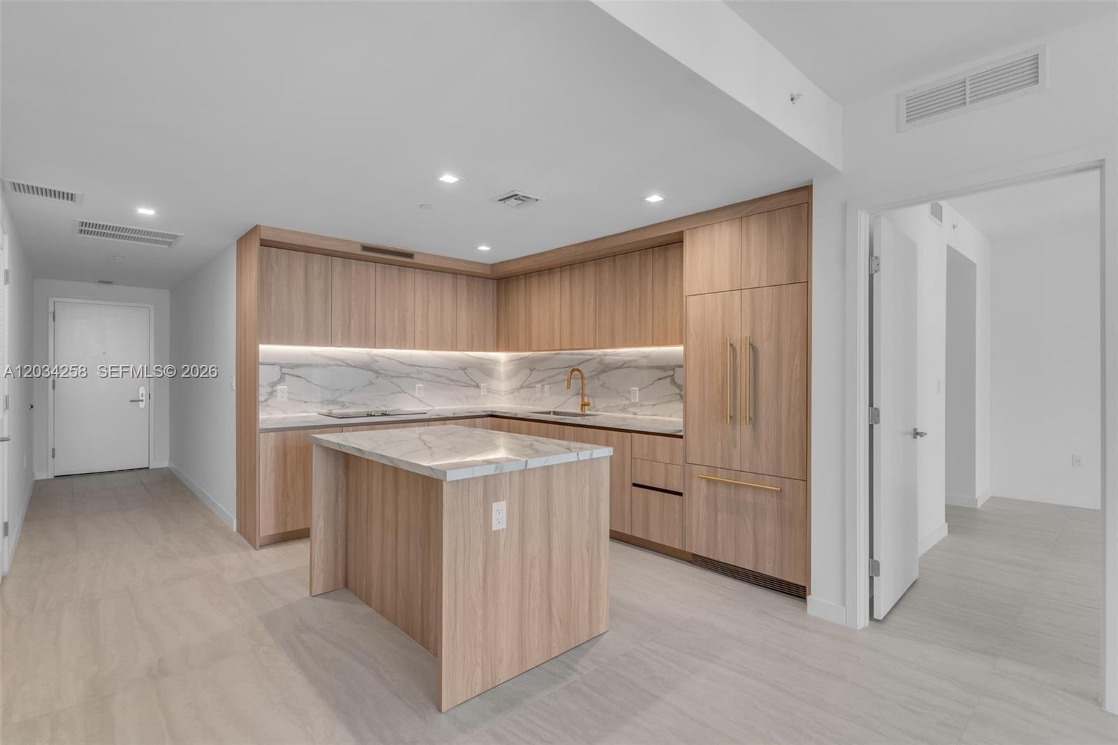 A modern kitchen features light wood cabinetry, marble countertops, and gold hardware — 77 SE 5 th st, Miami FL 33131, MIAMI, FL