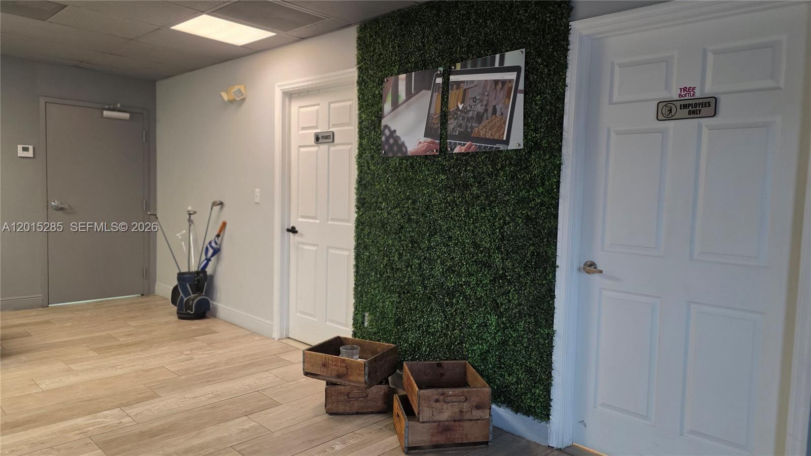 An office hallway features a green wall accent, wooden crates, and two white doors — 7762 NW 46th St, Doral FL 33166, DORAL, FL