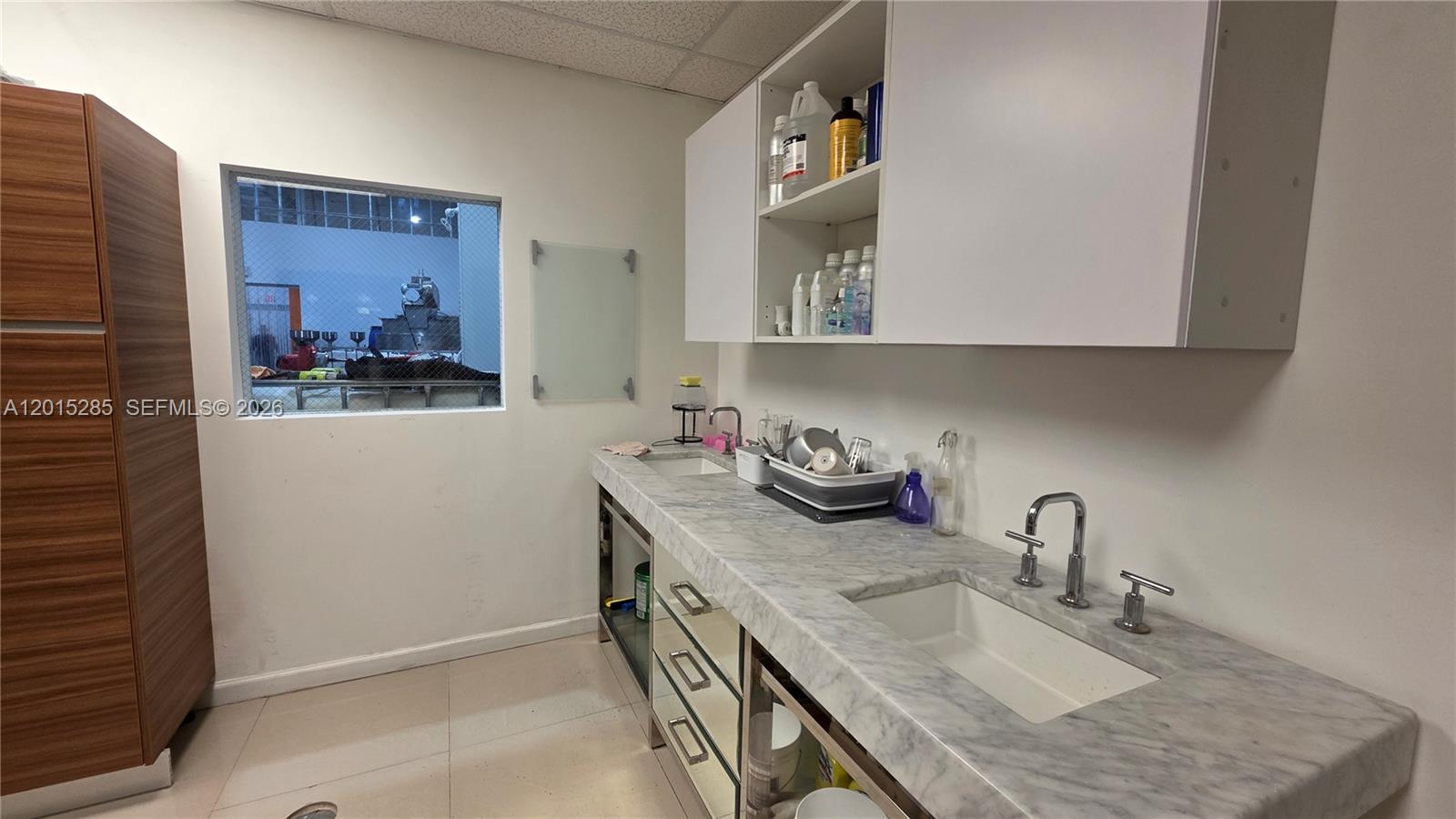 A utility room features a marble countertop, two sinks, white cabinets, and a window view — 7762 NW 46th St, Doral FL 33166, DORAL, FL