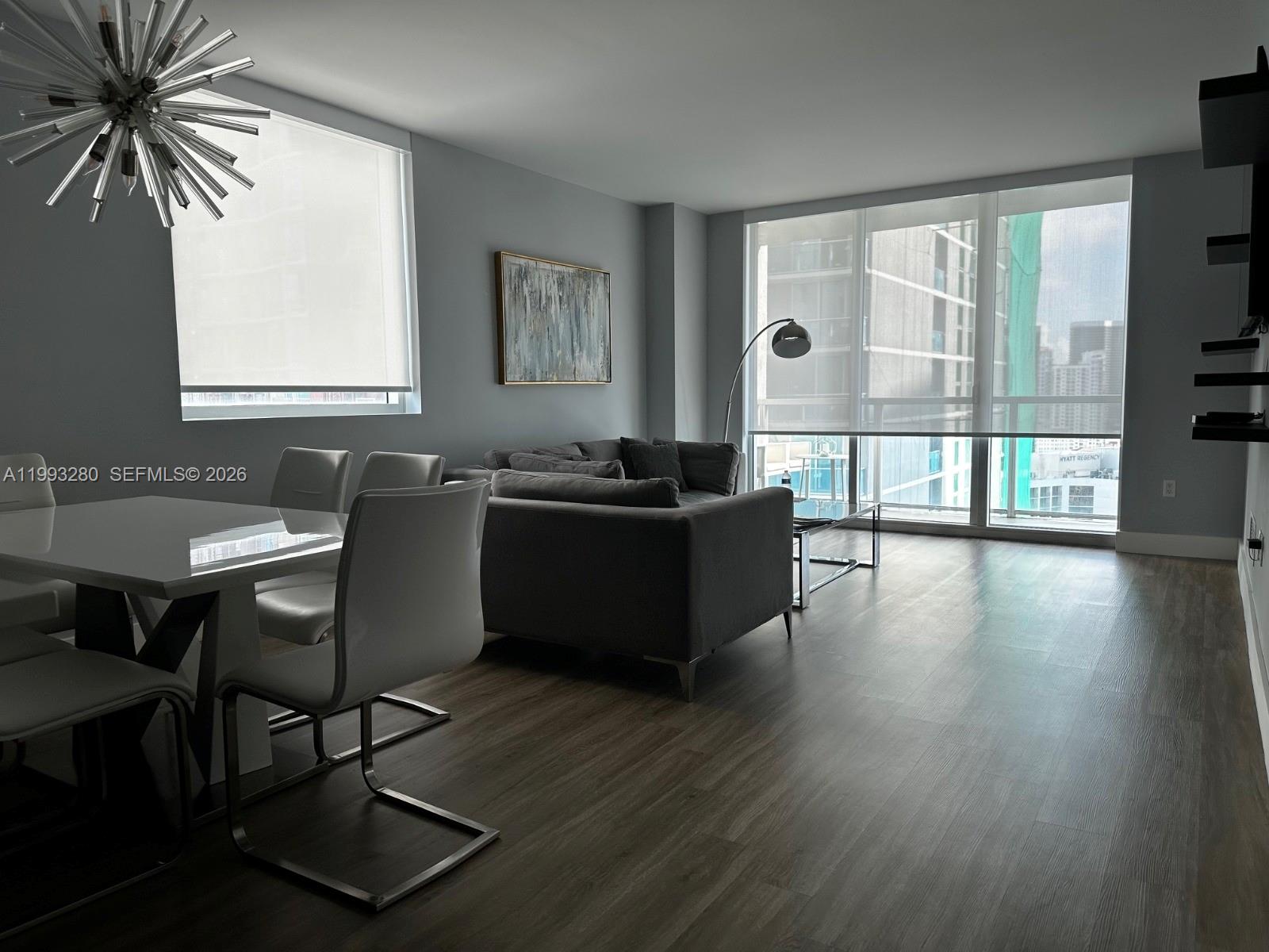 A modern living and dining area features gray walls, wood-look flooring, and floor-to-ceiling windows — 500 Brickell Ave # 3307, Miami FL 33131, MIAMI, FL