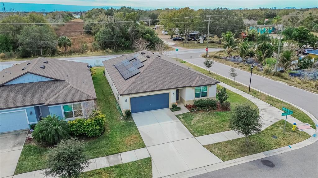 An aerial view shows two suburban houses with driveways and solar panels on one roof — 901 GOLDEN SHINER AVENUE, RUSKIN, FL