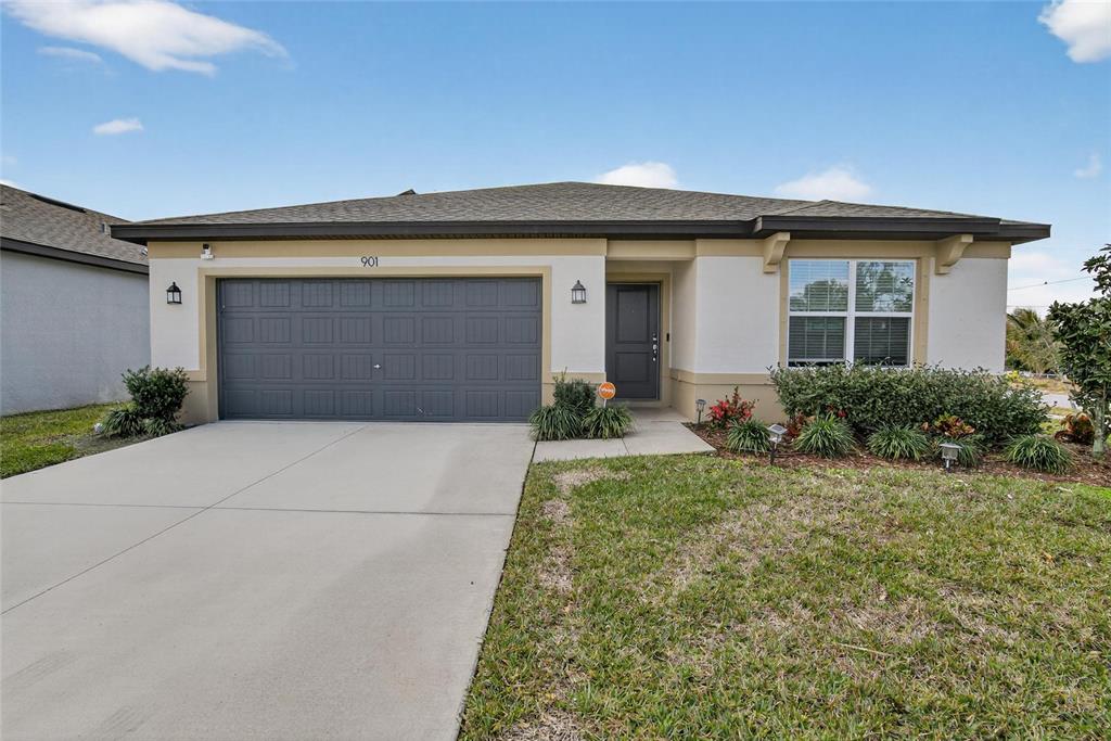 A single-story suburban house features a gray garage, beige stucco walls, and a front lawn — 901 GOLDEN SHINER AVENUE, RUSKIN, FL