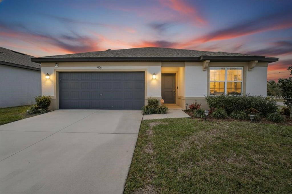 A single-story house with a two-car garage, white stucco exterior, and a concrete driveway — 901 GOLDEN SHINER AVENUE, RUSKIN, FL