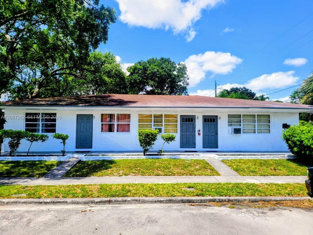 A single-story white duplex building with three dark gray doors and a grassy front yard — 2099 NE 172 St, North Miami Beach FL 33162, NORTH MIAMI BEACH, FL