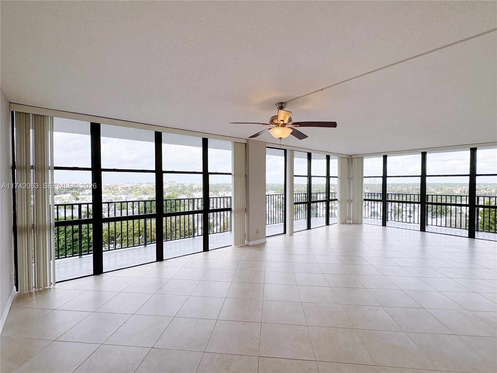 An expansive, empty room features light tile flooring, a ceiling fan, and floor-to-ceiling windows — 800 Parkview Dr # 909, Hallandale Beach FL 33009, HALLANDALE BEACH, FL