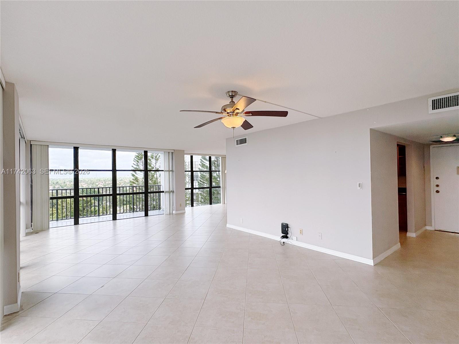 An empty room features light-colored tile flooring, a ceiling fan, and large floor-to-ceiling windows — 800 Parkview Dr # 909, Hallandale Beach FL 33009, HALLANDALE BEACH, FL
