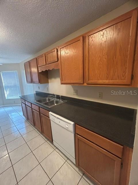 A kitchen features oak cabinets, dark countertops, a white dishwasher, and light-colored tile flooring — 563 HOLBROOK CIRCLE, LAKE MARY, FL