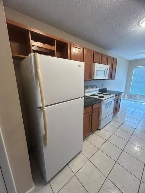 A kitchen features a white refrigerator, wooden cabinets, a microwave, and a white electric stove — 563 HOLBROOK CIRCLE, LAKE MARY, FL