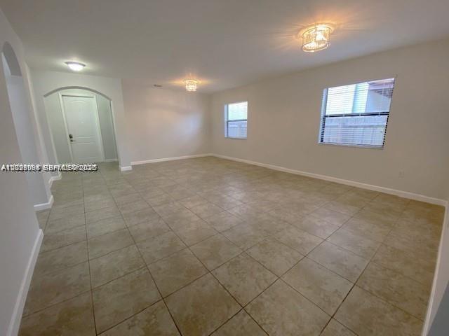 An empty room with beige tile flooring, white walls, and two windows — 15415 SW 175th St, Miami FL 33187, MIAMI, FL