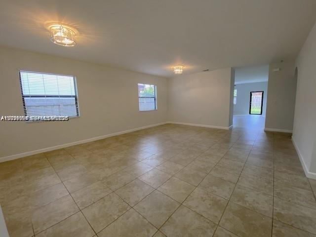 An empty room features beige tile flooring, two windows, and two decorative ceiling light fixtures — 15415 SW 175th St, Miami FL 33187, MIAMI, FL