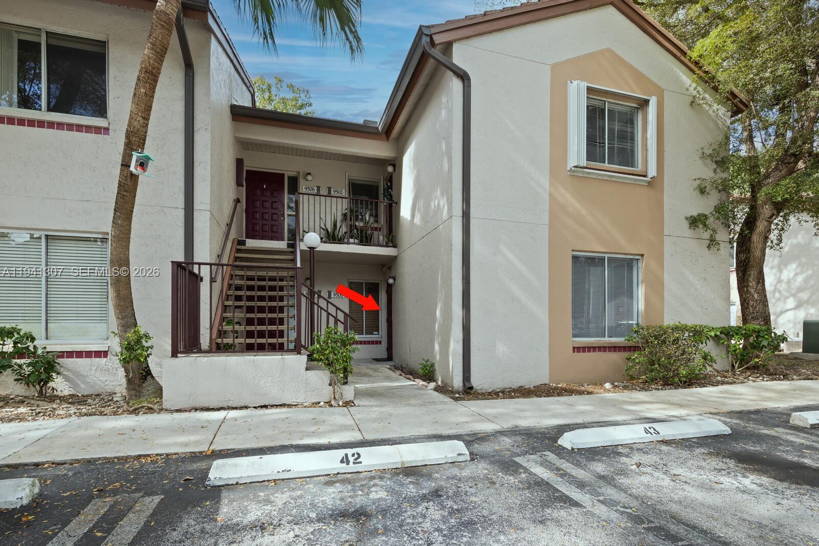 An exterior view of a two-story apartment building with a ground-level entrance marked by an arrow — 9500 SW 140th Ct # 9500, Miami FL 33186, MIAMI, FL