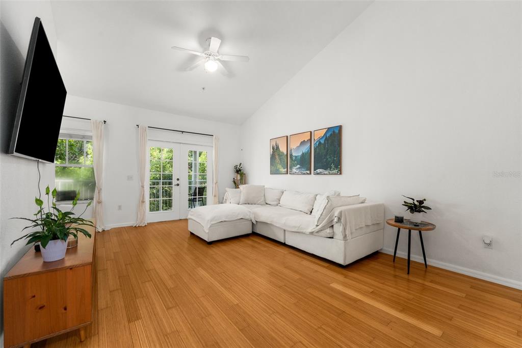 A living room features white walls, hardwood floors, a sectional sofa, and French doors — 9124 SW 51ST ROAD UNIT 302, GAINESVILLE, FL