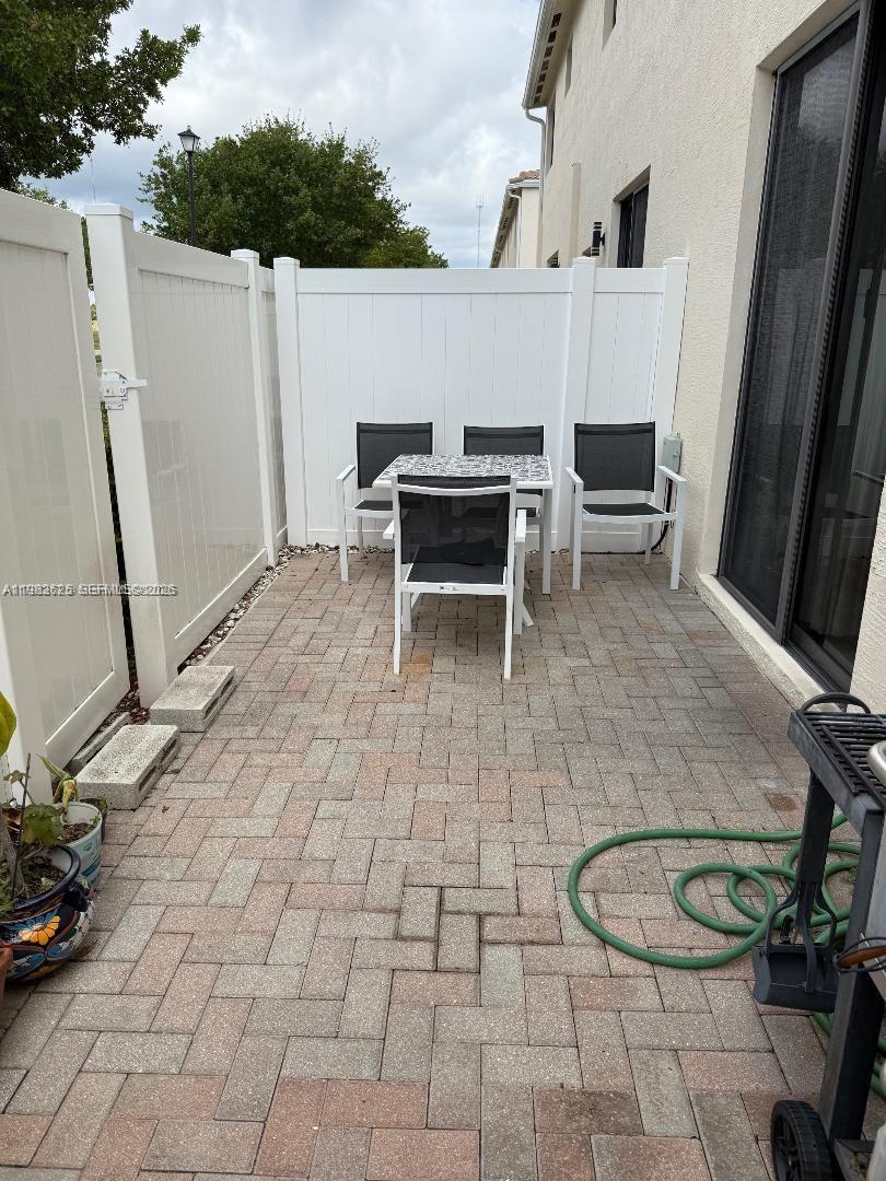 A small paved patio features a dining set and white vinyl privacy fencing — 424 NE 194th Ter, Miami FL 33179, MIAMI, FL