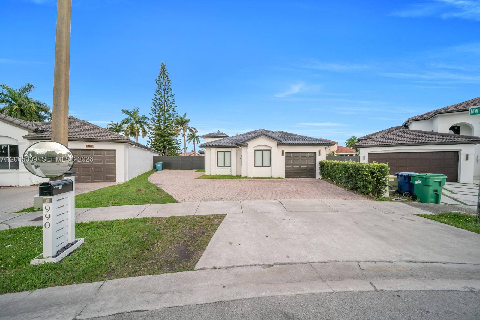 A single-story house with a paved driveway, a garage, and a lawn under a blue sky — 990 NW 131st Ave, Miami FL 33182, MIAMI, FL