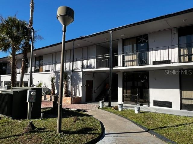 A two-story apartment building exterior features a concrete walkway, a tall lamp post, and palm trees — 8421 S ORANGE BLOSSOM TRAIL UNIT 441, ORLANDO, FL