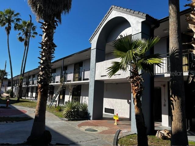 A multi-story apartment building exterior features a covered entryway, balconies, and several palm trees — 8421 S ORANGE BLOSSOM TRAIL UNIT 441, ORLANDO, FL