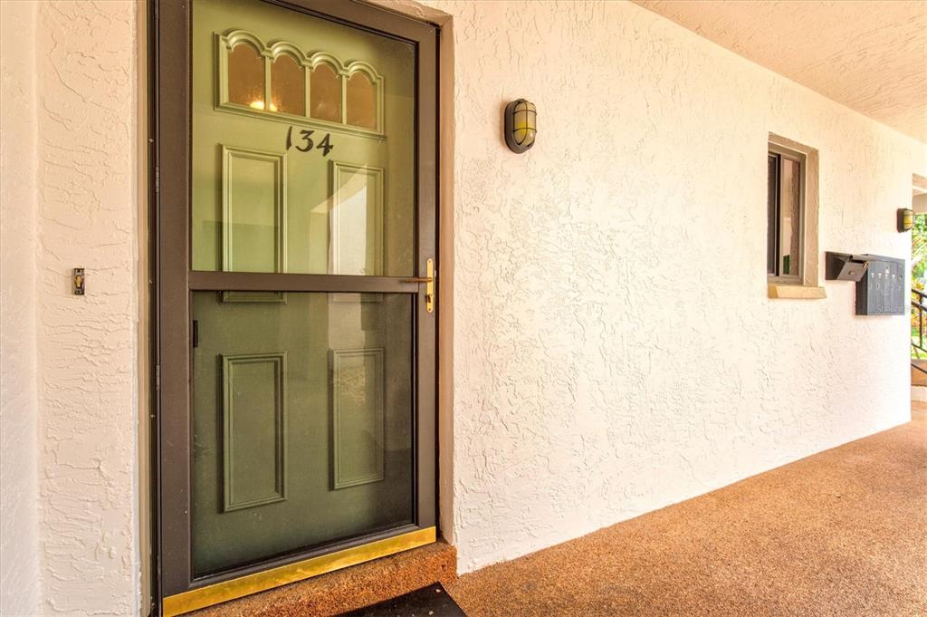 A front door with a screen door and the number 134 on a stucco building — 792 CAPRI ISLE BLVD UNIT 134, VENICE, FL